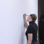 [a work that unfolds in four acts throughout the duration of the exhibition], pencil, drawing on the wall, performance, eraser, duration 30 days, dimensions variable (performer: Kirsten Harvey)
<br>
Performance still of the piece “Untitled” for the show “Imperceptible” curated by Xavier Acarín, at Abrons Art Center, New York
